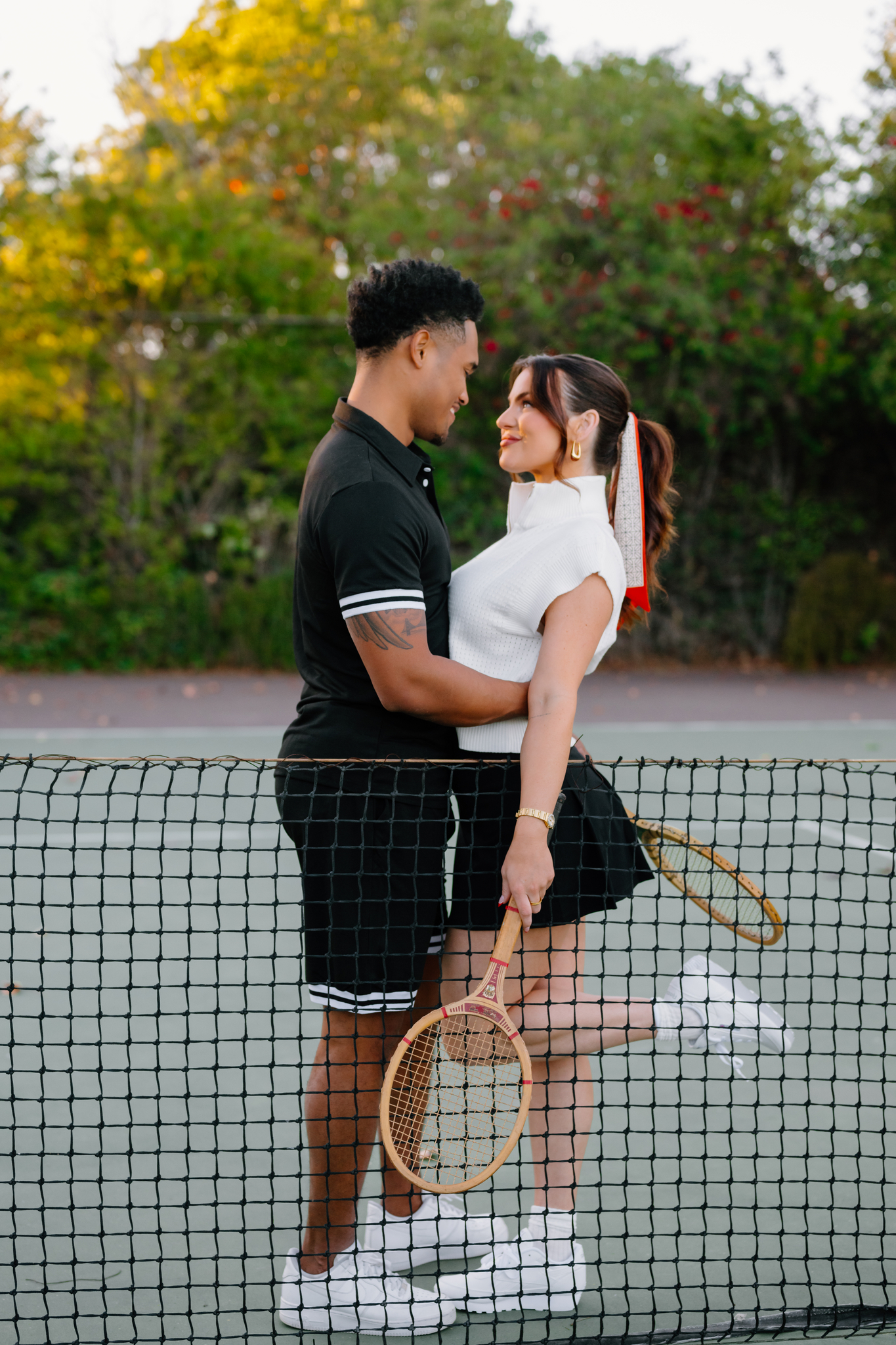 Couple embracing in a hug on a tennis court.